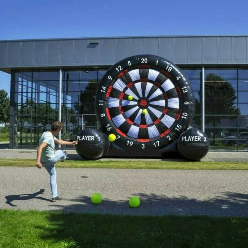 Our Big Impact Giant Inflatable Dartboard game set up to look visually impressive, with a man in action, kicking a football to get a score at a Corporate Fun Day event.