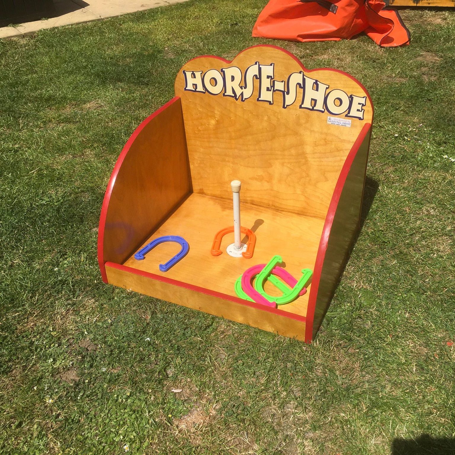 Our hired in Horseshoe Toss wooden game with colourful plastic horseshoes, positioned on the grass ready for play.