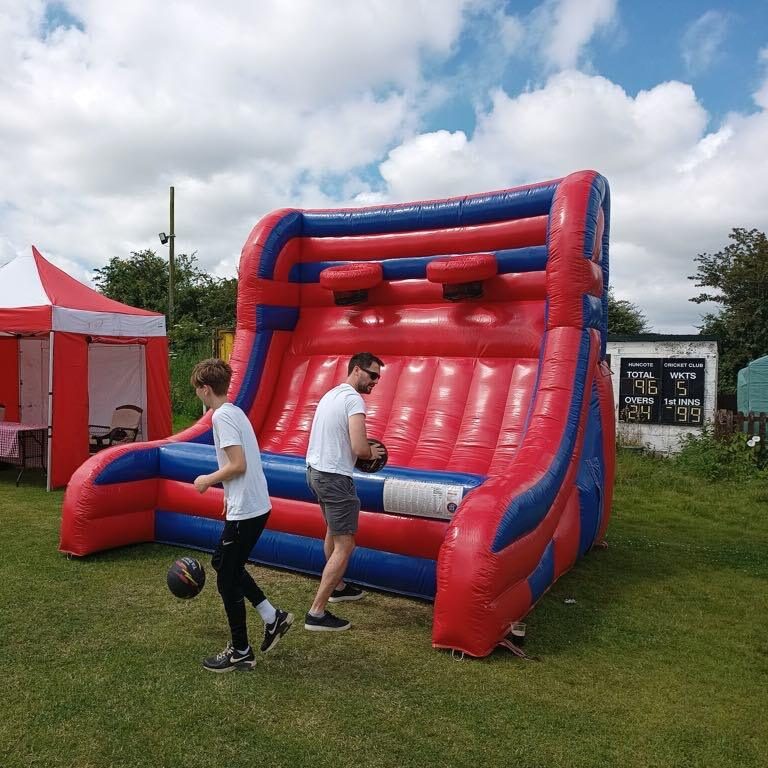 Two people playing with our large red and blue Inflatable Basketball game at a local Fete.