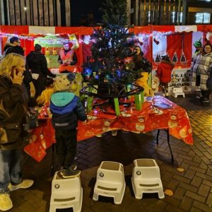 Christmas Market event outside with a Christmas Table, Christmas Tree and Festive Toys positioned for young children to enjoy close up, and our hired in Christmas Side Stalls in a row behind.