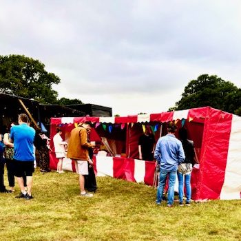 Summer event with our hired in red and white striped Fete Game Side Stalls in a row with people watching and playing