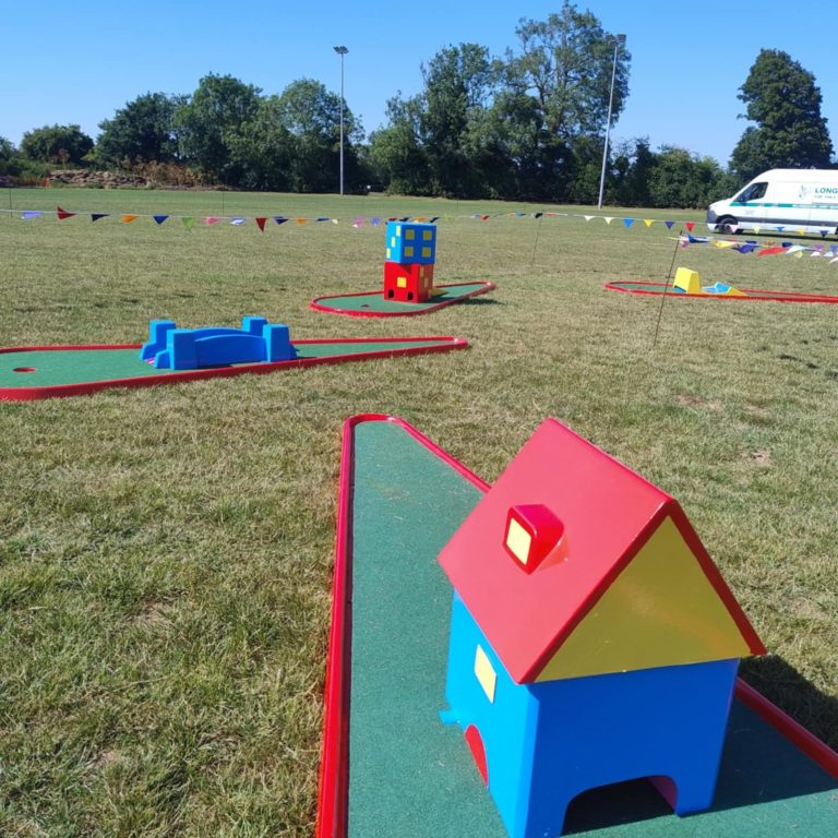 Our blue, red and yellow House Crazy Golf obstacle sat on a red base with artificial grass.