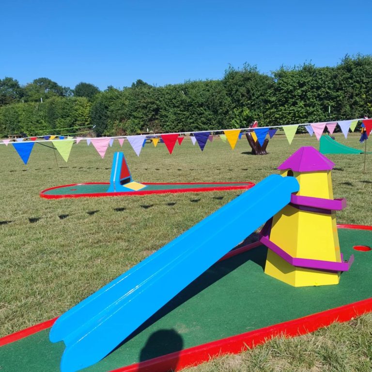 Our purple and yellow bright Helter Skelter Crazy Golf obstacle, with its blue ramp, sat on a red base with artificial grass.