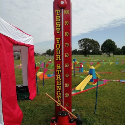 Traditional High Striker set up ready for play with a Side Stall, Crazy Golf and lots of bright bunting for a Village Fair or Fete.