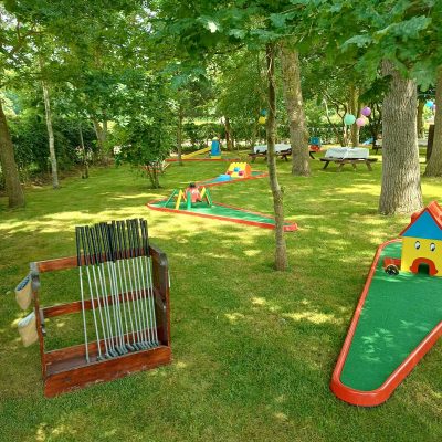 Our Crazy Golf with brightly painted obstacles set out on grass with lots of colourful bunting.