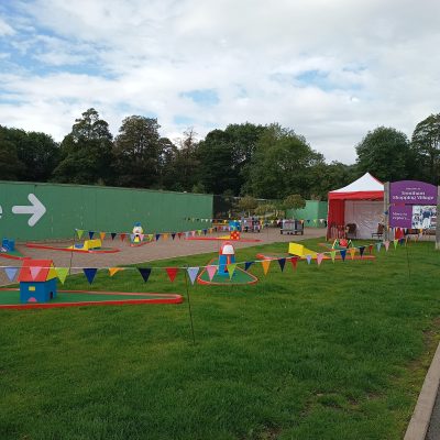 Our Crazy Golf with brightly painted obstacles set out on grass with lots of colourful bunting.