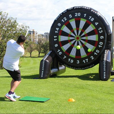Our Giant Inflatable Dartboard hired for an event with a man using his golf club to hit a golf ball at the target.