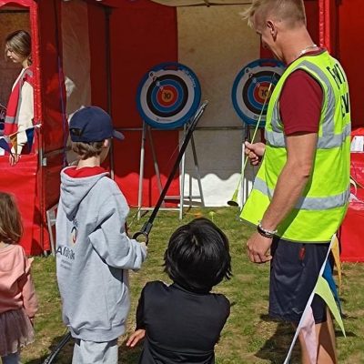 Safe Archery Children at a village fete playing soft archery, which is positioned inside one of our hired in Side Stalls, with bunting.