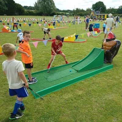 Gorilla Golf Putt Challenge Our infamous Gorilla Golf Putt Challenge with Crazy Golf in the background, decorated with brightly coloured bunting and happy, focused children playing.