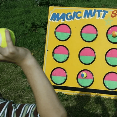 Magic Mitt A child stood in front of our brightly painted Magic Mitt game, with a ball poised ready for a throw.